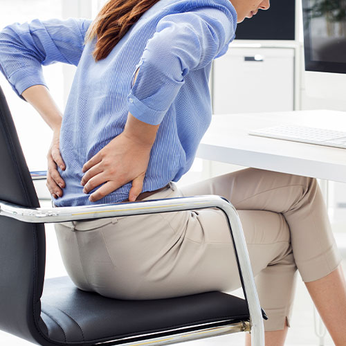 Woman sitting at a desk with lower back discomfort treated by back specialist Dr. Dipan in Parsippany-Troy Hills